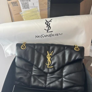 Svart axelväska från Saint Laurent - Inga defekter. Dustbag, kvitto, dokument och låda följs med vid köp. Köpt begagnad för några år sedan för 11 000kr och därav priset. Skriv vid funderingar ❣️mått: 17cm hög och 28cm bred