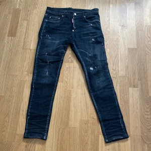 Svarta Dsquared2 jeans  - Dessa passar dig som är 170-175 kanske om du är 180. Snygga svarta  jeans från Dsquared2 med slitna detaljer och cool tvätt. Klassisk femficksmodell med Dsquared2-logga på bakfickan och röd etikett fram. Jeansen har låg midja och är tillverkade i stretchig denim för en tight passform.