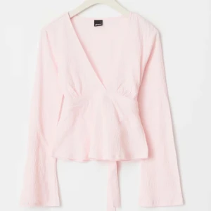 Ljusrosa omlottopp med knyt - Supersöt ljusrosa omlottopp från Gina Tricot med v-ringning och långa ärmar. Den är andvänd 2 gånger och är slutsåld på hemsidan. Hör av er vid frågor eller intresse