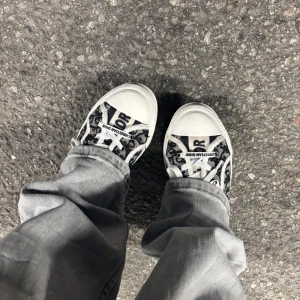 Mnogram sneakers - Snygga sneakers med svartvitt monogrammönster, vita snören och detaljer i vitt gummi. Klassisk rund tå och platt sula. Ikonisk logga på både häl och snörning. Perfekta för dig som vill sticka ut med lyxig streetstyle.(pris går att diskutera)