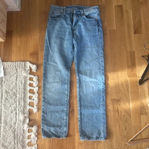 Levi's 551 ljusblå jeans straight fit - Ljusblå Levi's 551 jeans med klassisk straight fit och femficksdesign. Jeansen har normal midja, snygga kontrastsömmar och ikonisk läderpatch bak. Perfekta för dig som gillar en tidlös och avslappnad look.