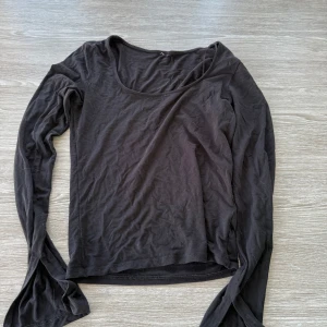 Svart långärmad basic tröja - En svart långärmad tröja med rund halsringning. Modellen är enkel och tight, perfekt att styla med jeans eller kjol. Tillverkad i mjuk bomull som känns skön mot huden. En klassisk baströja som funkar året runt.