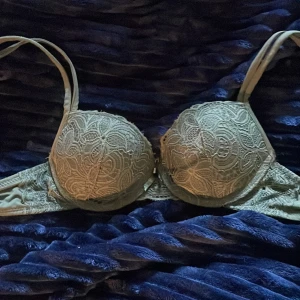 Grön spetsig bh - Snygg grön bh med vadderade kupor och vackert spetsmönster framtill. Axelbanden är justerbara och toppen har en feminin, figurnära passform. Perfekt för att lyfta din outfit med en touch av elegans.