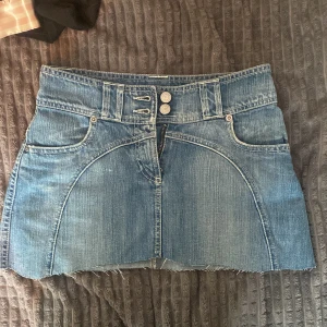 Blå jeanskjol från Zoul, stl 34 - Snygg blå jeanskjol från Zoul med rå kant nertill och coola broderade bakfickor. Passar perfekt för både sommaren och hösten. Aldrig använd!💕