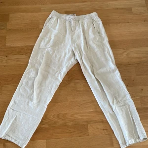 Beige linnebyxor från H&M med snörning - Luftiga beige linnebyxor från H&M med elastisk midja och snörning. Byxorna har raka ben, sidfickor och en bakficka. Perfekta för varma dagar när du vill ha en chill och stilren look.