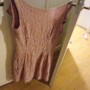 Ljusrosa spetsklänning från Roco - Säljer en ljusrosa kortklänning från Roco i storlek 40. Klänningen har ett vackert spetsmönster och är ärmlös med rund hals. Kjoldelen har lätt utställd form som ger en feminin siluett. Perfekt för dig som gillar romantisk stil och mjuka färger.