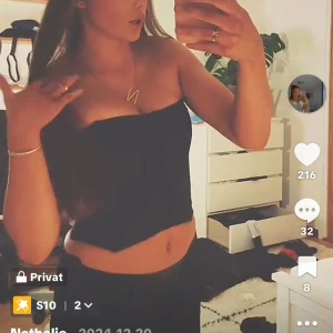 Svart korsett-topp med mönster - Säljer en svart axelbandslös korsett-topp med diskret blommigt mönster. Toppen är croppad och har en tight passform som framhäver midjan. Perfekt att styla med jeans eller kjol för en trendig look.