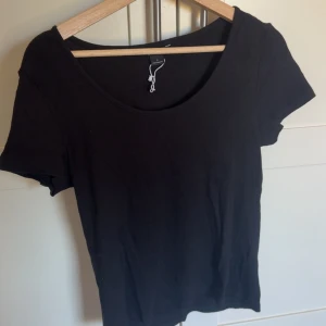 Svart kortärmad topp från Monki - En basic svart topp från Monki i storlek L. Modellen har rund halsringning och korta ärmar, perfekt att matcha med jeans eller kjol. Tillverkad i mjuk bomull som känns skön mot huden. Enkel och stilren design som funkar till allt. Toppen är ej använd och tvättas innan den skickas, säljs då jag inte gillar den