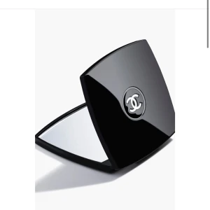 Svart sminkspegel från Chanel - Supersnygg sminkspegel från Chanel i stilren svart design med den ikoniska loggan i silver på locket. Perfekt storlek för att ha med i väskan och enkel att fälla upp. Spegeln har en lyxig känsla och passar dig som gillar exklusiva accessoarer.