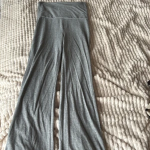 Grå yoga pants från Gina Tricot - Grå mjukisbyxor från Gina Tricot som man viker ner med bred linning. Byxorna har en loose passform och raka, vida ben. Tillverkade i mjukt bomullsmaterial som är superbekvämt för chill eller träning.