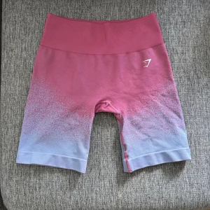 Gymshark rosa-lila seamless shorts - Snygga seamless shorts från Gymshark i en cool rosa till lila ombre. Hög midja och tight passform som sitter på plats under träning. Mjukt och stretchigt material som känns skönt mot huden. Perfekta för gymmet eller löprundan.