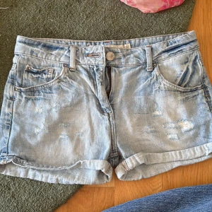 Ljusblå jeansshorts från Zara Woman - Snygga ljusblå jeansshorts från Zara Woman med slitna detaljer och uppvikta benslut. Klassisk femficksmodell med dragkedja och knapp framtill. 