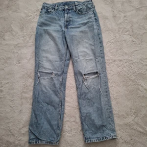 Ljusblå loose fit jeans från H&M - Ljusblå jeans från H&M i loose fit med raka ben och justerbar midja. Snygga slitningar och hål vid knäna ger en avslappnad vibe. Klassisk femficksmodell i mjuk bomullsdenim. Perfekta för dig som gillar en chill och trendig look. Byxorna har tyvärr ett litet streck på framsidan som kanske kan gå bort med vanish, men vet ej för jag har aldrig testat vanish!
