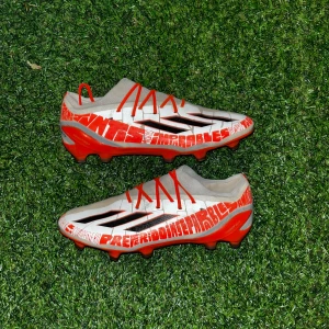 Adidas speedportal.1 Messi  - Snygga Adidas fotbollsskor med vit ovandel, röda detaljer och svarta ränder. Skorna har röda snören och textgrafik längs sidorna. Lätta och smidiga med platt sula och dobbar för bästa grepp på planen. Perfekta för dig som vill sticka ut på matchen. Skick8/10 (priset kan diskuteras!)