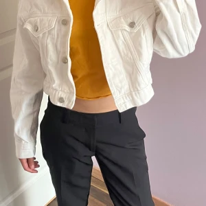 Vit croppad jeansjacka från Gina tricot - Säljer en vit croppad jeansjacka från Gina tricot i storlek XS. Jackan har klassisk krage, silvriga knappar framtill och på bröstfickorna samt långa ärmar. Perfekt att slänga över en t-shirt för en chill look.