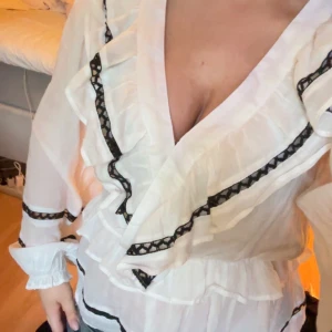 Neo Noir blus - Fin vit blus med svart brodering som detalj. Används inte, därför säljs och har aldrig använts. Från Neo Noir. Nypris: 749