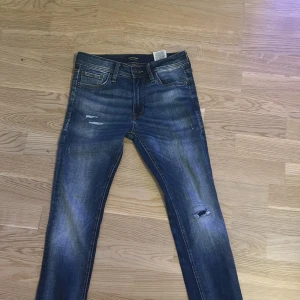 Blå skinny jeans från Jack & Jones - Snygga blå skinny jeans från Jack & Jones med slitna detaljer och lätt tvättad look. Klassisk femficksmodell, normal midja och stretchigt jeanstyg som sitter tajt hela vägen ner. Perfekta för dig som gillar en modern och avslappnad stil Storleken är 29/30 men sitter som 27/30. Skriv för frågor 🙌🏻😁.
