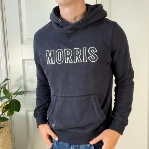 Morris hoodie  - Morris hoodie i storlek S, modellen är 180,75 kg. Hoodien har tecken på användning men inga hål eller liknande. Skick, 7/10. Ljuset blev lite konstigt på vissa bilder men hoodien är hel svart. Kom med frågor! 