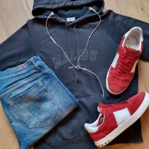 Saint Laurent Malibu hoodie - Säljer en svart hoodie från Saint Laurent med 'MALIBU' broderat på bröstet. Tröjan har huva med snörning, känguruficka och långa ärmar. Tillverkad i mjuk bomull, perfekt för chill dagar och streetstyle.