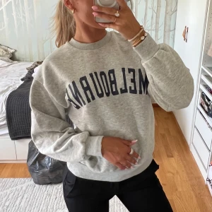 Grå sweatshirt från Gina Tricot - Säljer en ljusgrå sweatshirt från Gina Tricot i storlek XS med mörkblå text 'MELBOURNE' framtill. Tröjan har rund hals, ribbade muddar och en loose fit. Perfekt för chill dagar och enkel att styla. Knappt använd 🙌🏽💞