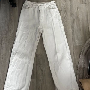 Vita raka jeans med hög midja - Säljer ett par vita jeans med raka ben och hög midja. Byxorna har klassisk femficksdesign och stängs med knapp och dragkedja. Perfekta för en clean och fräsch look året runt.