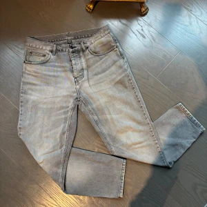 Grå jeans från Carhartt - Snygga grå jeans från Carhartt i klassisk femficksmodell. Jeansen har raka ben och normal passform, med bälteshällor och dragkedjegylf. Perfekta till en avslappnad streetstil och funkar året runt.
