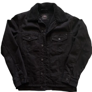 Svart jeansjacka från Zara - Svart jeansjacka från Zara med mjuk teddykrage och foder. Klassisk modell med knappar framtill och två bröstfickor med lock. Perfekt för dig som vill ha en stilren jacka med extra värme och cool vibe. Använd endast en gång. storlek S