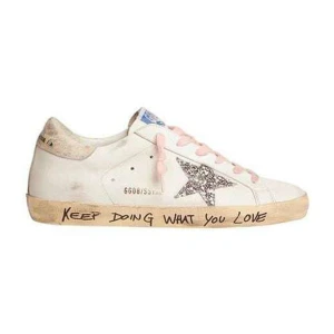 Golden Goose sneakers med glitterstjärna - Snygga vita sneakers från Golden Goose med rosa snören och en glittrig stjärna på sidan. Sulan har handskriven text och en vintage-look. Perfekt för dig som gillar unika detaljer och streetstyle. Skorna är tillverkade i skinn och har rund tå.