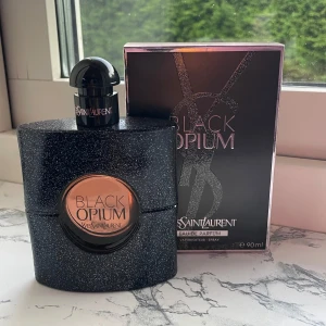 Yves Saint Laurent Black Opium parfym - Black Opium Eau de Parfum från Yves Saint Laurent i en glittrig svart flaska med rund kopparfärgad detalj och svart kork. Doften är ikonisk och flaskan känns lyxig och modern. Kommer i originalkartong på 90 ml. Endast testad med ca 3 sprut. 