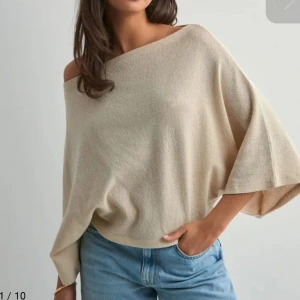 Beige poncho topp med vida ärmar - Säljer en supermjuk beige topp med poncho och vida trekvartsärmar. Toppen har en loose passform och är perfekt för en classy look. Materialet känns lätt och luftigt.