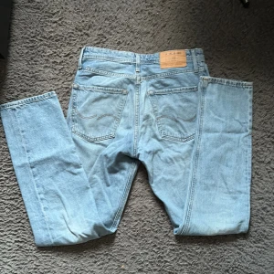 Ljusblå loose fit jeans Jack & Jones - Säljer ett par ljusblå jeans från Jack & Jones, modell Loose/Chris. De har en avslappnad loose fit, klassisk femficksdesign och raka ben. Jeansen är tillverkade i bomull och har snygga kontrastsömmar. Perfekta för en chill och avslappnad stil.
