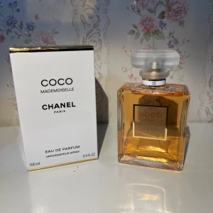 Chanel Coco Mademoiselle EdP 100ml - Chanel Coco Mademoiselle Eau de Parfum i 100 ml flaska. Klassisk, fyrkantig glasflaska med guldig etikett och frostad, rundad kork. Parfymen har en varm bärnstensfärgad ton och levereras med originalkartong i vitt med gulddetaljer.