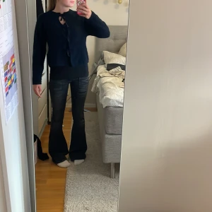 Mörkblå kofta med rosetter  - mörkblå kofta från Gina Tricot med grovstickad känsla och flera söta knytband framtill. (Långärmad)