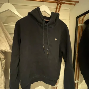 Svart hoodie från Morris Stockholm - Svart hoodie från Morris Stockholm med huva och snörning. Tröjan är i storlek M men passar S. 