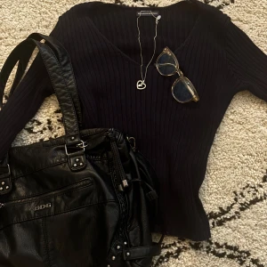 Mörkblå ribbad tröja från Brandy Melville - Snygg mörkblå ribbad tröja från Brandy Melville med v-ringad hals och långärmad passform. Tröjan är slim och sitter riktigt nice på kroppen. Perfekt att styla med jeans eller kjol för en chill look. Materialet är mjukt och stretchigt, troligtvis bomull eller syntet.