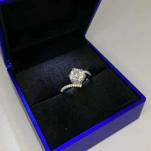 Äkta silver 925s ring med stor glittrande sten  - Snygg silver ring i äkta silver 925s med en stor rund glittrande sten i mitten och små stenar längs bandet. Ringen har en modern och lyxig känsla, perfekt för dig som gillar att sticka ut. Aldrig använd utan kommer från min small business. 