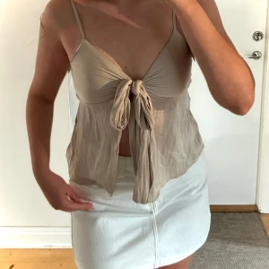 Knyttopp - Gina Tricot - Säljer en stilren knyt-top från Gina Tricot i storlek 38. Toppen har en vacker design med en knytning i fronten som ger en feminin och trendig look. Den är perfekt för sommarens fester eller en avslappnad dag i stan. Kombinera med kjol eller jeans för en komplett outfit! Nästan ny, använd en gång. Ingen synlig slitage.