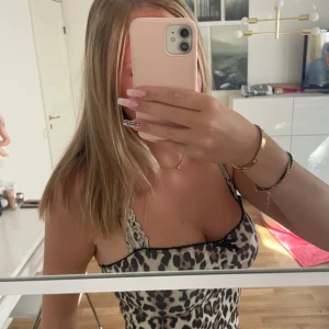 Leopardmönstrat linne Gina Tricot - Snygg leopardmönstrat linne från Gina Tricot i storlek S. Linnet har tunna axelband, svart spetskant upptill och en liten rosett i mitten. Materialet är mjukt och glansigt.