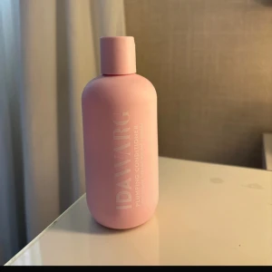 Ida Warg rosa plumping conditioner - Snygg rosa flaska med plumping conditioner från Ida Warg. Flaskan har en rund form och är tillverkad i plast med vit text. Perfekt för dig som vill ge håret extra volym och vård med en trendig look i badrummet. (‼️Halva kvar)