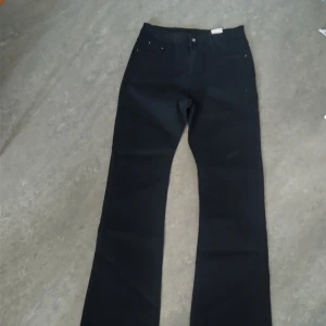 Svarta bootcut jeans i storlek 30 - Snygga svarta jeans med bootcut passform och klassisk femficksdesign. Jeansen har en stilren look med svarta sömmar och bälteshällor. Perfekta för dig som gillar en tidlös och clean stil. Materialet är jeans och färgen är helsvart.