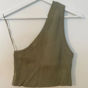 Olivgrön ribbad oneshoulder topp - Snygg croppad topp i olivgrönt med ribbad struktur och oneshoulder-design. Mjuk och stretchig.