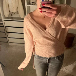 Ljusrosa omlottstickad tröja - Supermysig ljusrosa stickad tröja med omlott-design och knyt i sidan från ASOS Det går att välja vilken sida man vill knyta en rosett på! Knappt använd 