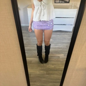 Ljuslila paljettkjol - Supersöt ljuslila kortkjol med glittriga paljetter över hela ytan. Kjolen är tight och har en mjuk insida i syntetmaterial som gör den bekväm att bära. Perfekt för dig som vill sticka ut med lite extra sparkle och färg.