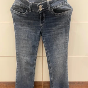 Blå bootcut jeans med broderade fickor från Nelly - Snygga blå jeans med bootcut passform och coola broderade detaljer på bakfickorna. Jeansen har klassisk femficksdesign, normal midja och är tillverkade i mjukt denimtyg. Perfekta för dig som gillar en avslappnad men trendig look. Jeansen är från Nelly, Storlek 36- Small