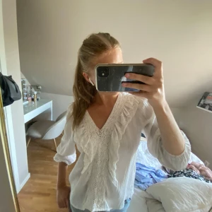 Vit blus med spets och volang från Zara - Supersöt vit blus från Zara med v-ringning, spetsdetaljer framtill och volanger längs bröstet. Nästan aldrig använd och o super fint skick🩷