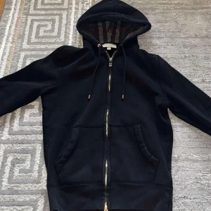 Burberry hoodie - Säljer denna feta Burberry hoodien i storlek XS med klassiskt rutigt foder i huvan. Tröjan är eftertraktad. Den är använd bara några få gånger och är därför i väldigt bra skick. Den är i storlek XS. Den är självklart äkta, men kvitto saknas. Pris kan diskuteras