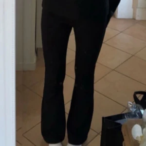 Svarta bootcut kostymbyxor  - Snygga svarta byxor med bootcut-snitt som ger en trendig siluett. Byxorna har en klassisk passform och är perfekta för dig som gillar stilrena och enkla plagg. Passar till sneakers eller boots för en cool look. 