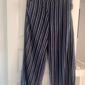 Randiga vida byxor Holly & Whyte S - Mörkblå byxor med vita ränder från Holly & Whyte. Vida ben och relaxed fit, perfekta för en chill och snygg look. Gjorda i ett lätt och luftigt tyg som känns skönt mot huden. Klassisk midja och elastisk baktill för extra komfort.100%viskos 