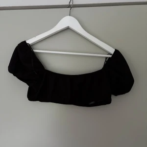 Svart croppad bolerotopp - Trendig svart bolerotopp med puffiga korta ärmar och croppad passform. Perfekt för att styla över linnen eller klänningar för en cool layering-effekt. Enkel och stilren design som passar till många outfits.