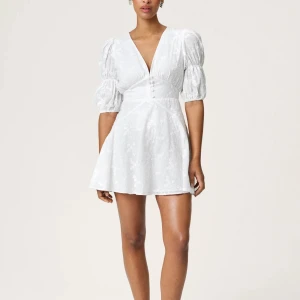 Vit kort klänning med puffärm - Superfin vit kortklänning med v-ringning, puffiga korta ärmar och markerad midja. Klänningen har broderade blommor, knappar framtill och lätt utsvängd kjol. Perfekt för sommarens alla tillfällen! Klänning är liten i storlek så mer som en 36/38 i storlek💕